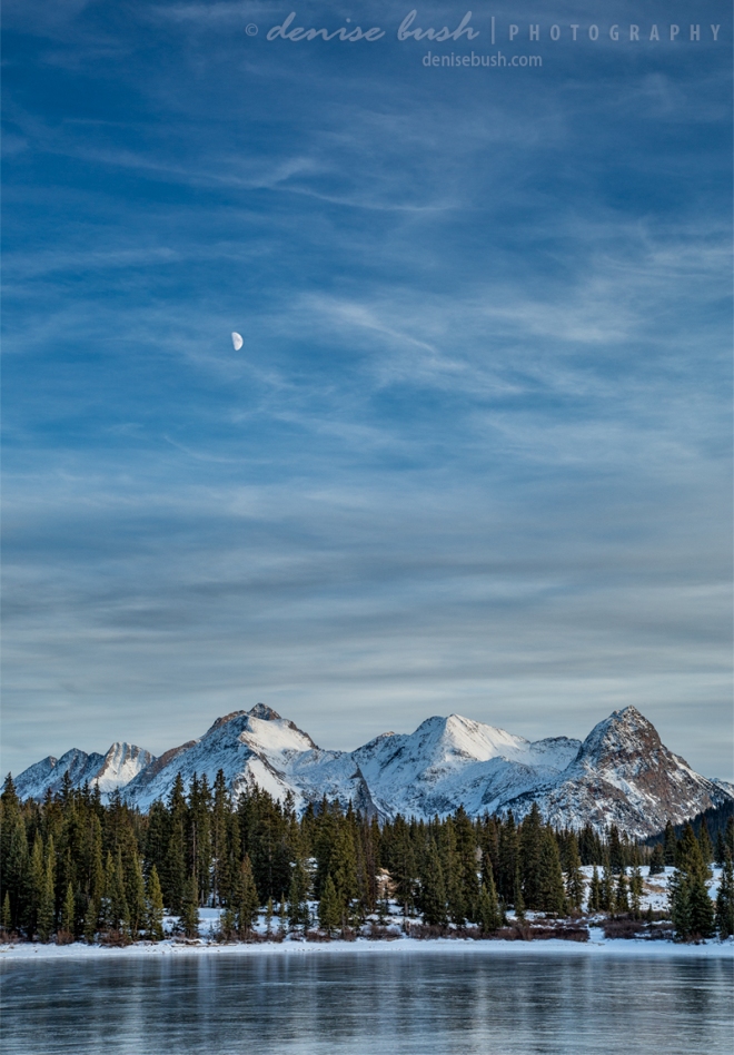 A setting moon floats above snow-covered mountains across Molas Lake near Silverton, Colorado.