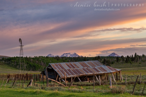 An old barn looks on the brink of collapse under a spring sunset sky.