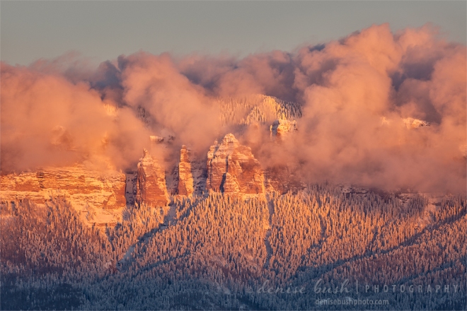 The warm light of alpenglow illuminates the snow-covered rocks and beautiful pink clouds.